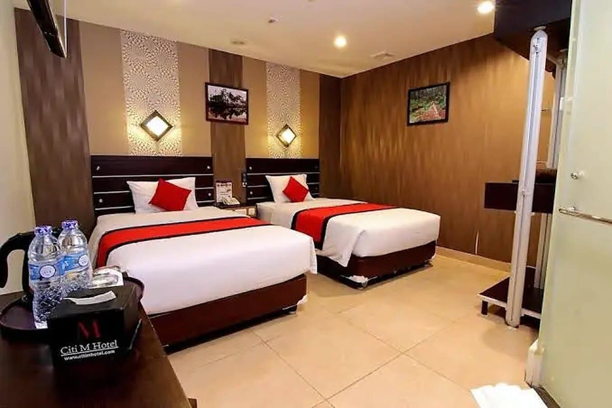 Kamar twin dengan bantal merah dan area kerja